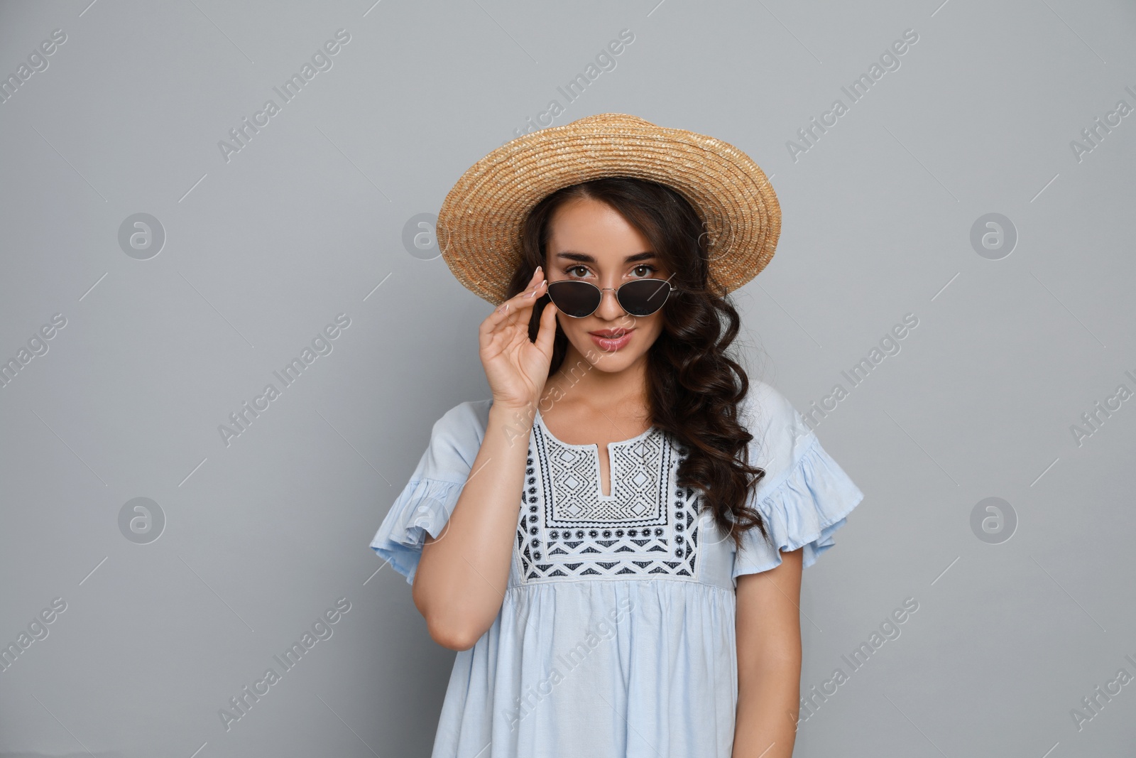 Photo of Beautiful young woman with straw hat and stylish sunglasses on light grey background