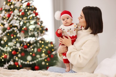 Happy young mother with her cute baby on bed, space for text. Winter holiday