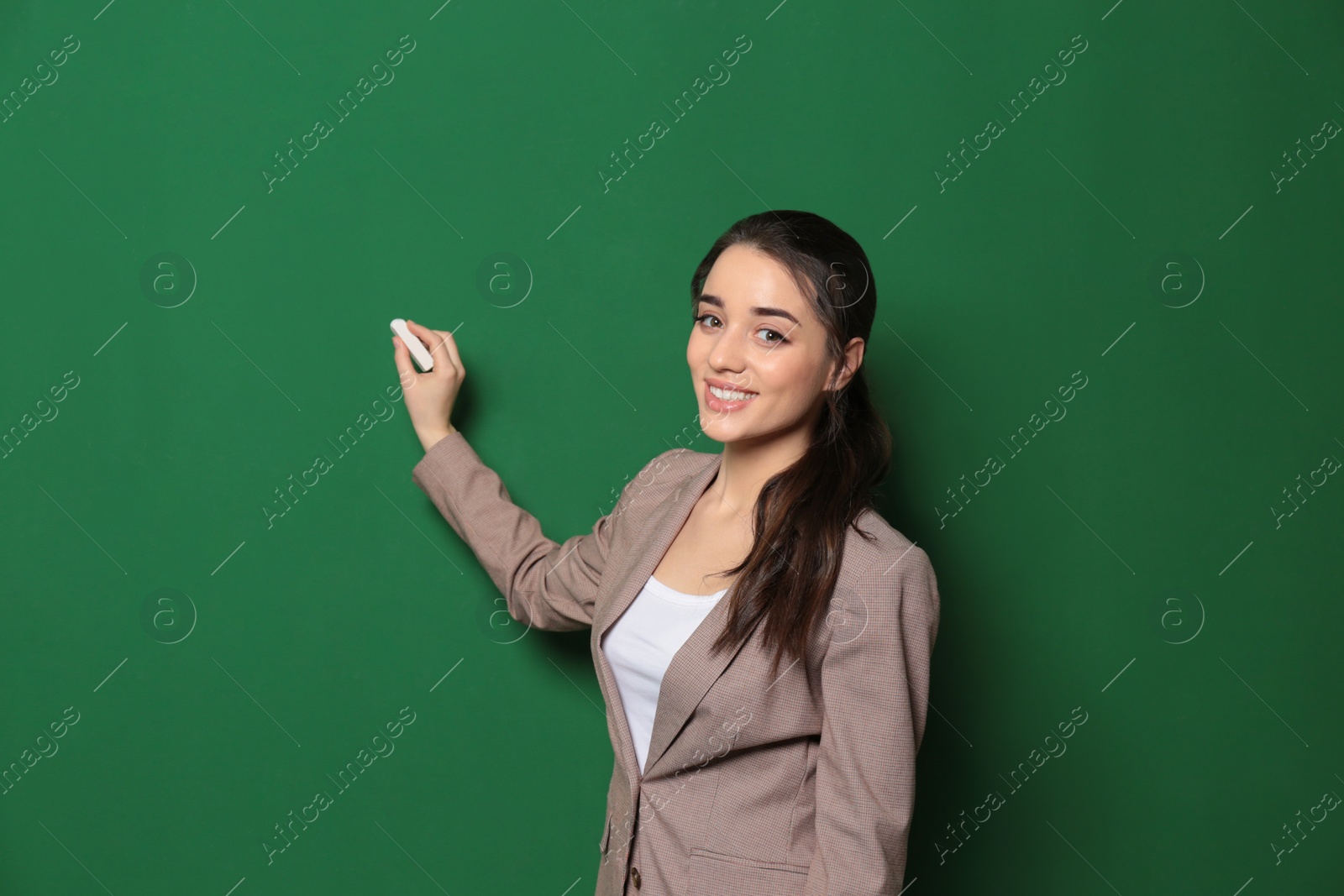Photo of Portrait of beautiful young teacher writing on chalkboard