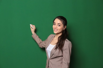 Portrait of beautiful young teacher writing on chalkboard