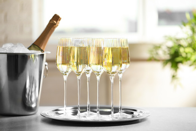 Photo of Glasses of champagne and ice bucket with bottle on grey table