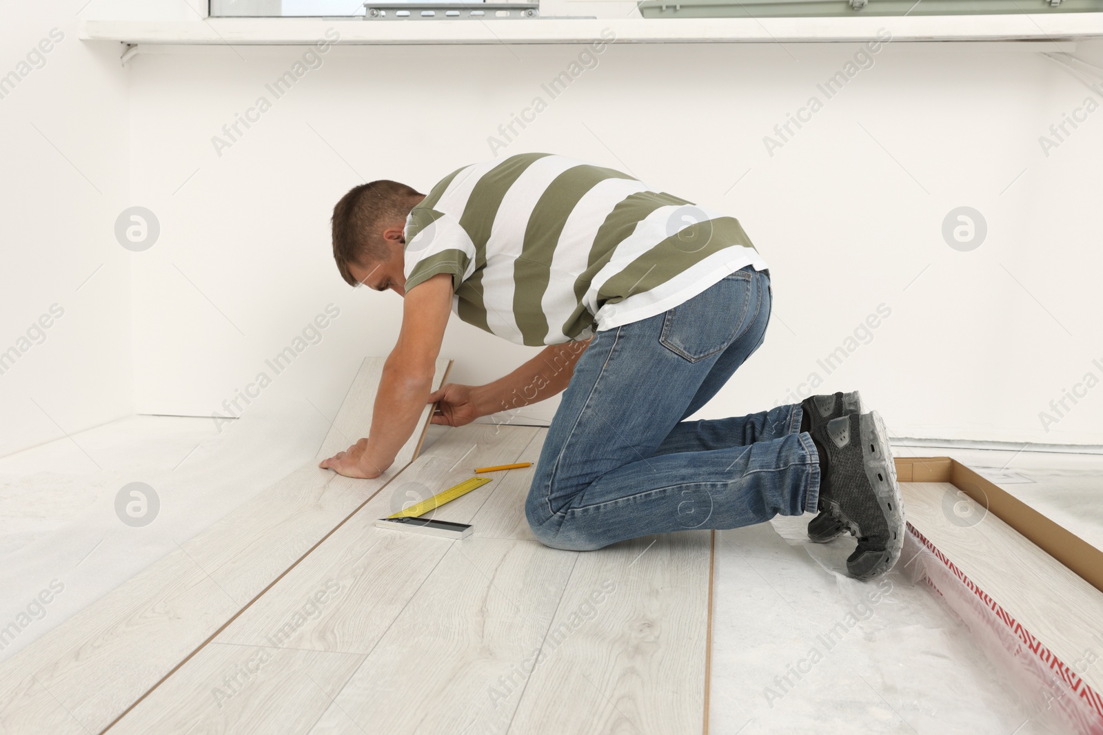 Photo of Professional worker installing new laminate flooring indoors