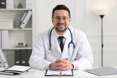 Photo of Smiling doctor working at white table in clinic