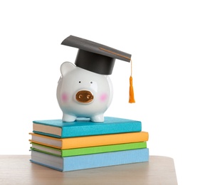 Photo of Piggy bank with graduation hat and books on table against white background