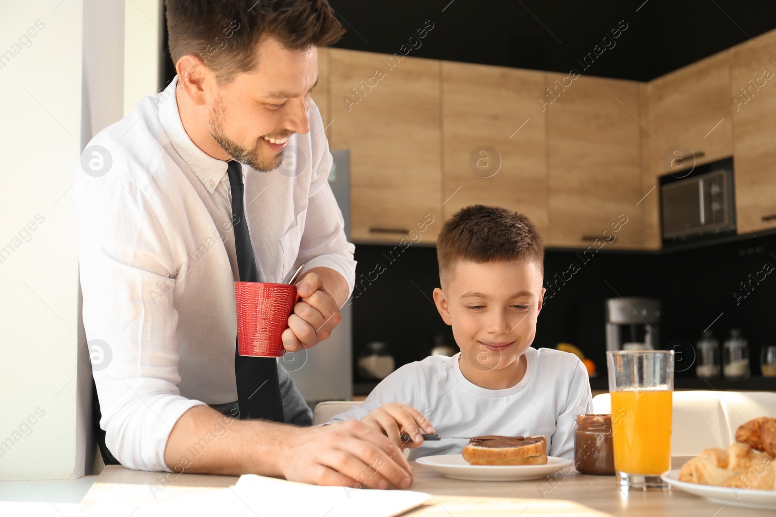 Photo of Dad and son having breakfast together in kitchen