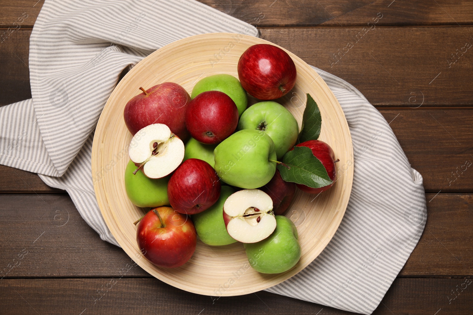 Photo of Plate with fresh ripe apples and leaves on wooden table, top view
