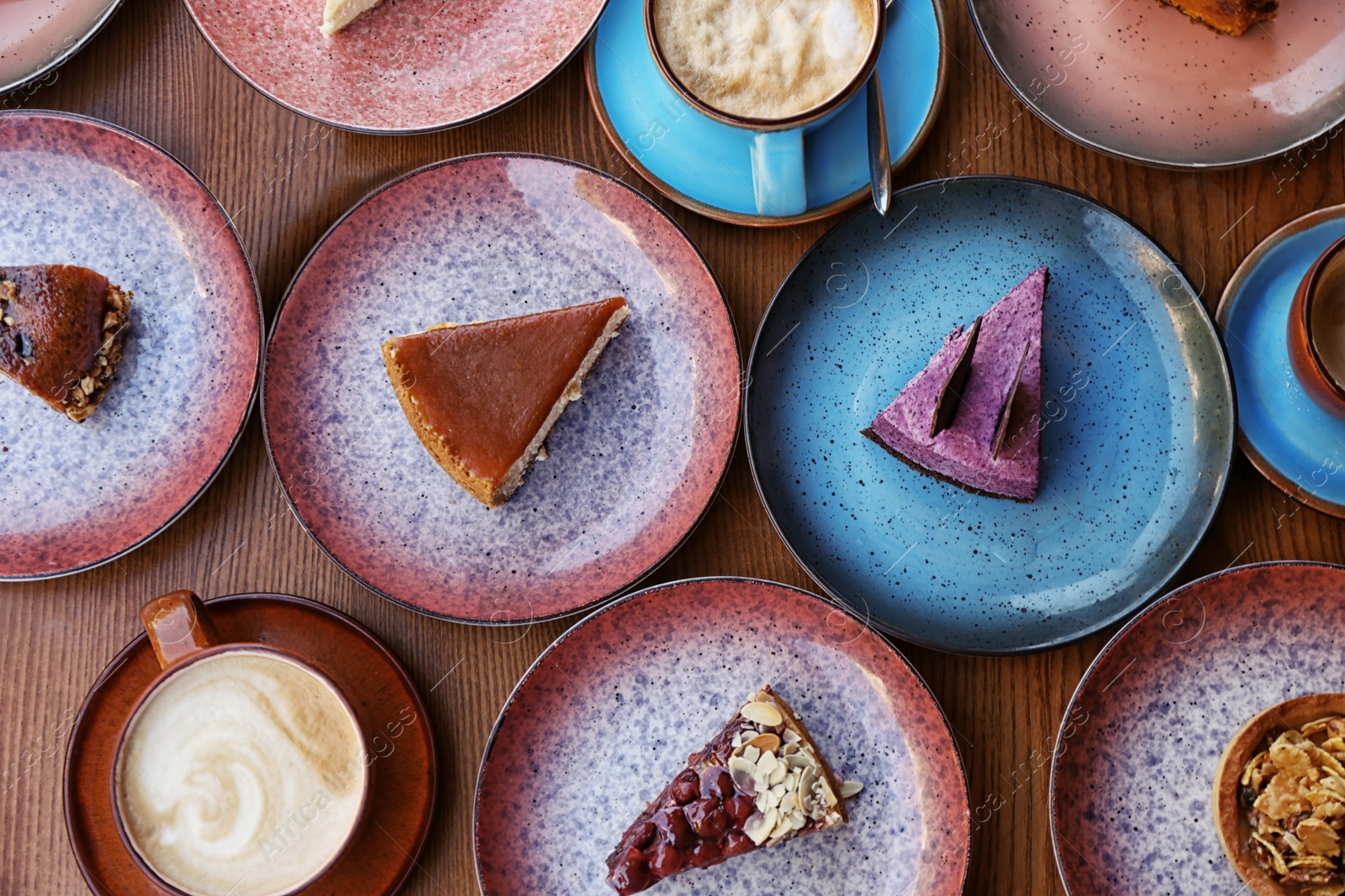 Photo of Plates with different cakes and aromatic coffee on wooden table, top view