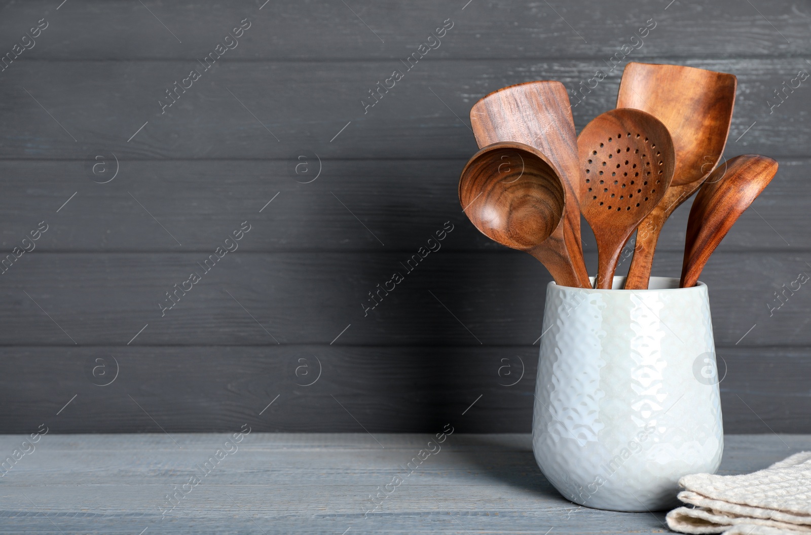 Photo of Set of kitchen utensils in holder on grey wooden table, space for text