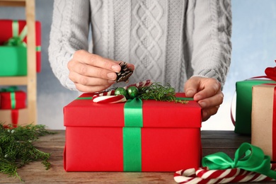 Woman wrapping Christmas gift at wooden table indoors, closeup