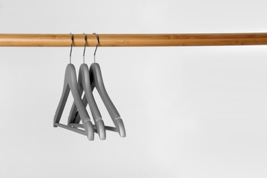 Photo of Wooden rack with clothes hangers on white background, space for text