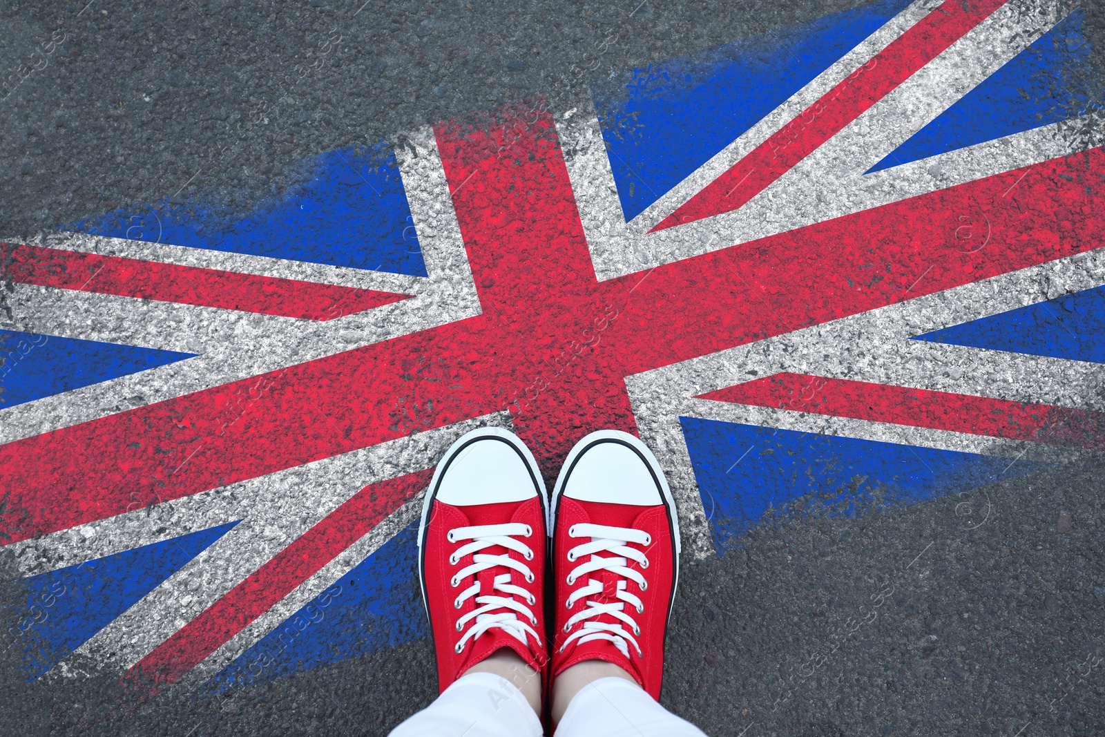 Image of Immigration. Woman standing on asphalt near flag of United Kingdom, top view