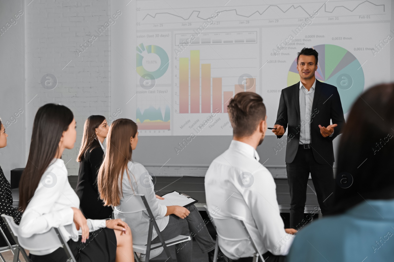 Photo of Male business trainer giving lecture in conference room with projection screen