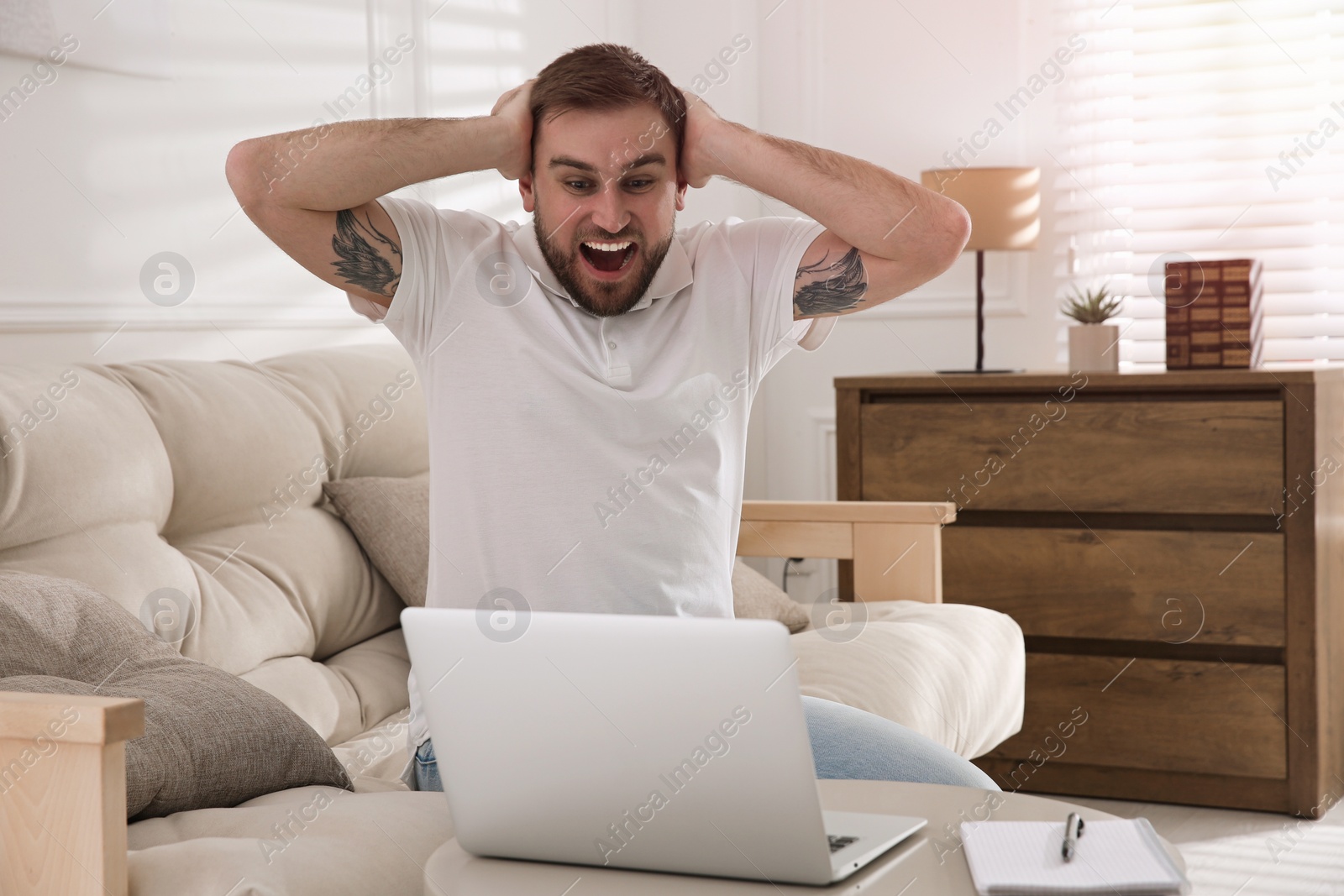 Photo of Emotional man participating in online auction using laptop at home