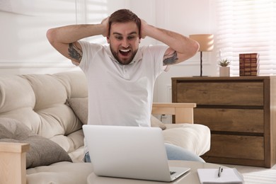 Emotional man participating in online auction using laptop at home