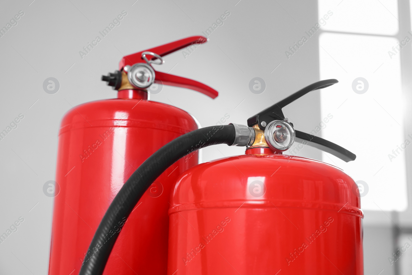 Photo of Two red fire extinguishers indoors, closeup view