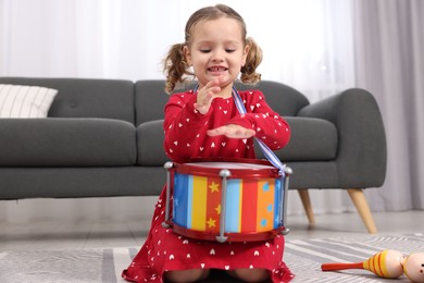 Photo of Little girl playing toy drum at home