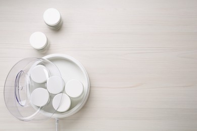 Photo of Modern yogurt maker with jars on white wooden table, flat lay. Space for text