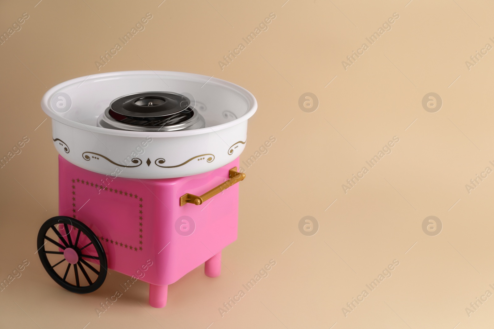 Photo of Portable candy cotton machine on beige background, space for text