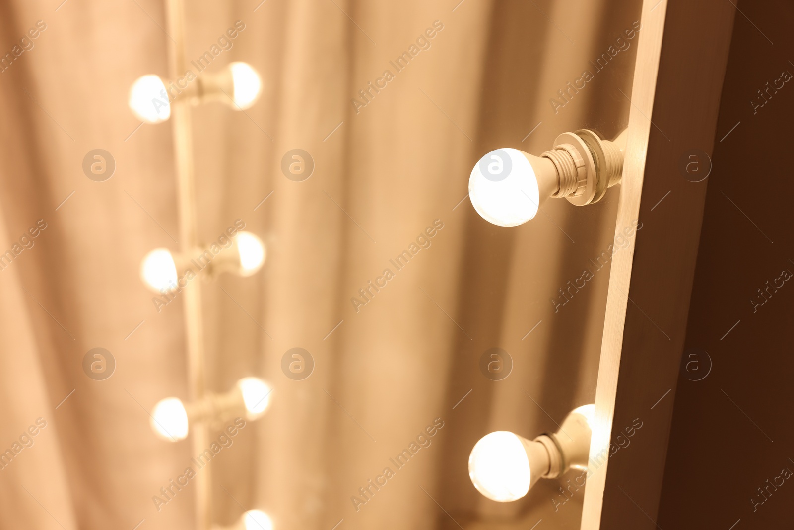 Photo of Modern mirror with light bulbs in makeup room, closeup