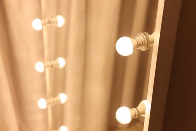 Photo of Modern mirror with light bulbs in makeup room, closeup