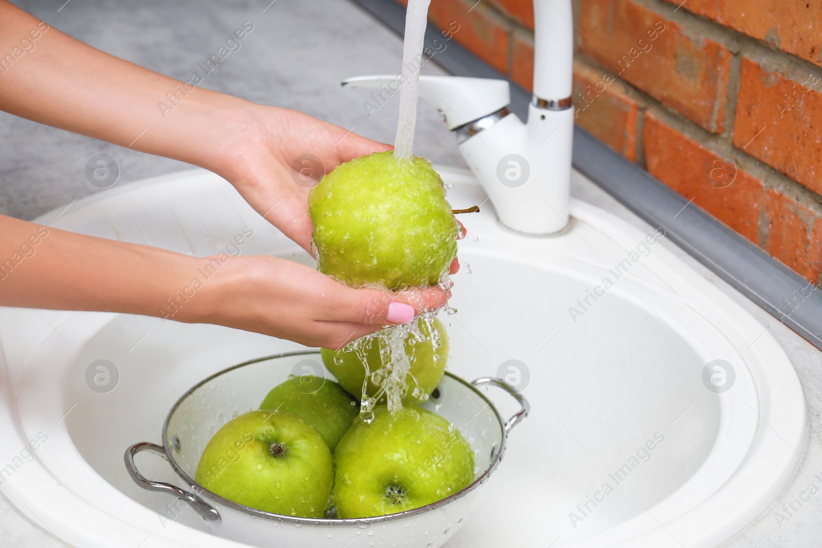 Photo of Woman washing fresh apples in kitchen sink, closeup