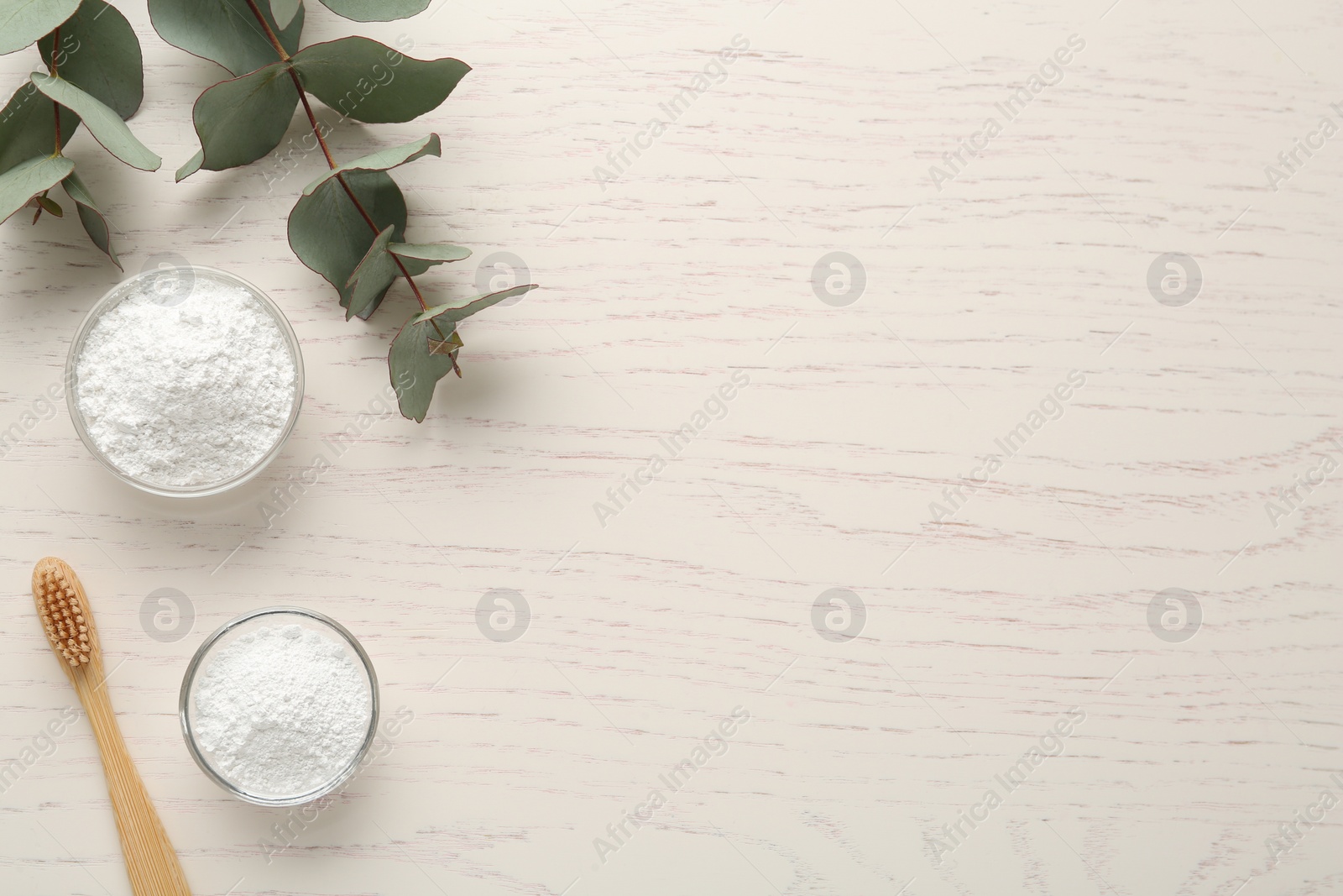 Photo of Tooth powder, brush and eucalyptus on white wooden table, flat lay. Space for text