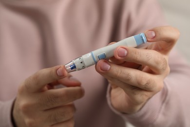 Diabetes test. Man checking blood sugar level with lancet pen, closeup