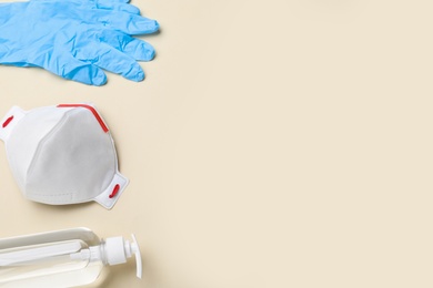 Medical gloves, respiratory mask and hand sanitizer on beige background, above view. Space for text