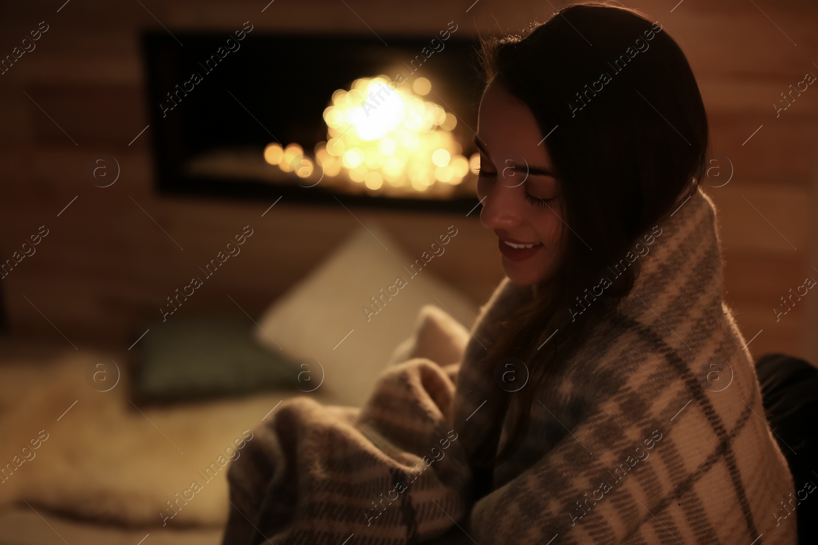 Photo of Young woman resting near decorative fireplace at home. Winter season