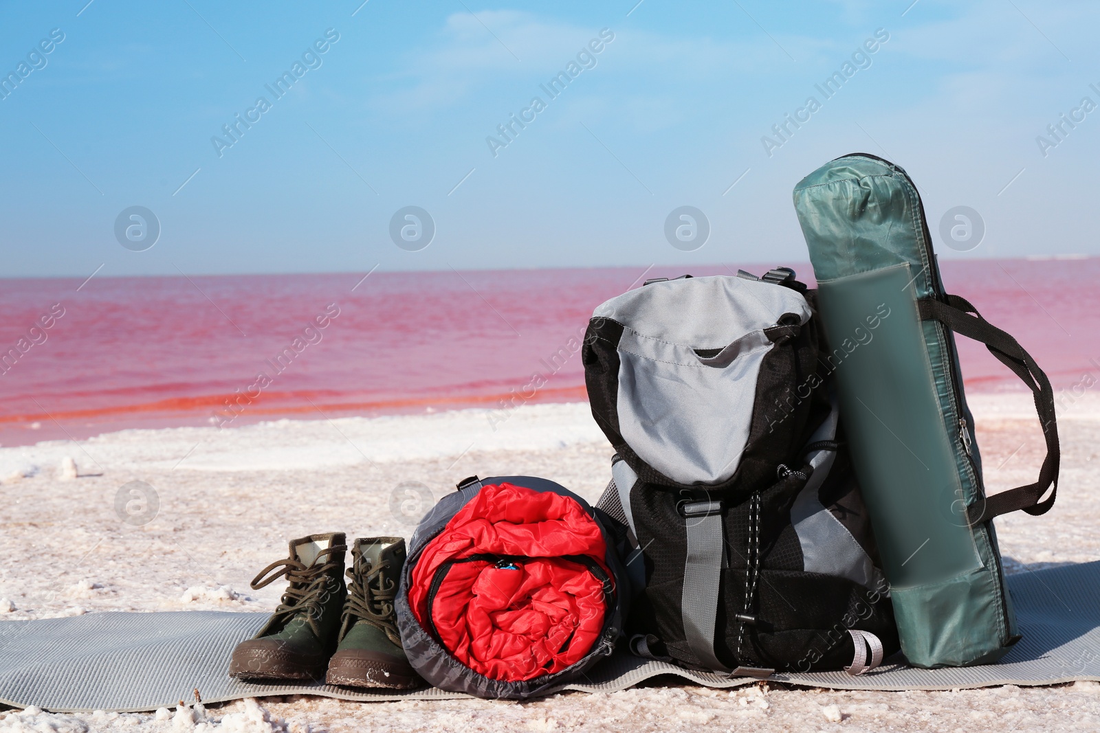 Photo of Set of camping equipment with sleeping bag on coast of pink lake