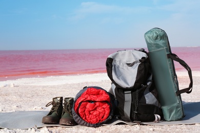 Set of camping equipment with sleeping bag on coast of pink lake