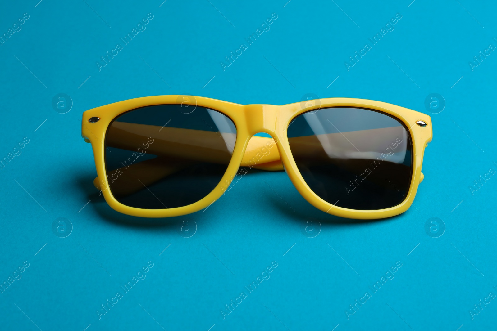 Photo of Stylish sunglasses on blue background. Fashionable accessory