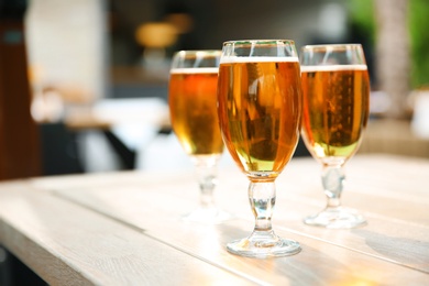 Photo of Glasses with cold beer on table against blurred background