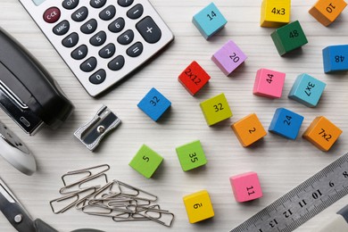 Photo of Colorful cubes with numbers and stationery on white wooden table, flat lay