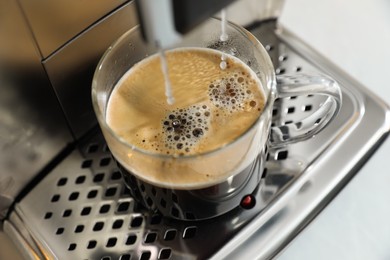 Modern coffee machine making espresso into cup, closeup