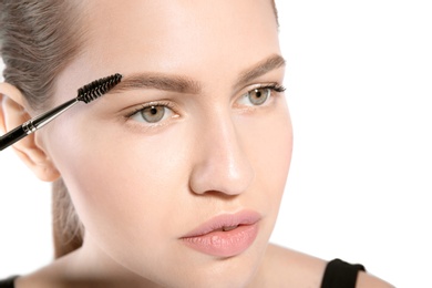 Photo of Beautiful woman with perfect eyebrows applying makeup on light background