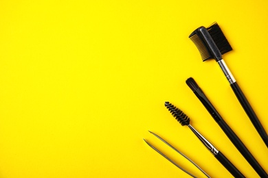 Photo of Set of professional eyebrow tools on yellow background, flat lay. Space for text