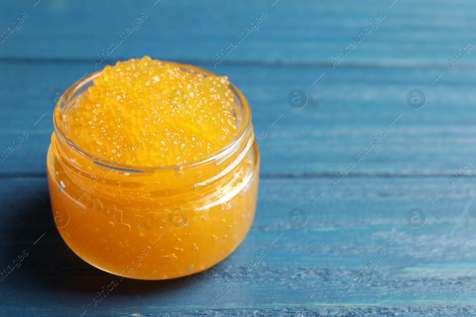 Photo of Fresh pike caviar in glass jar on blue wooden table, space for text