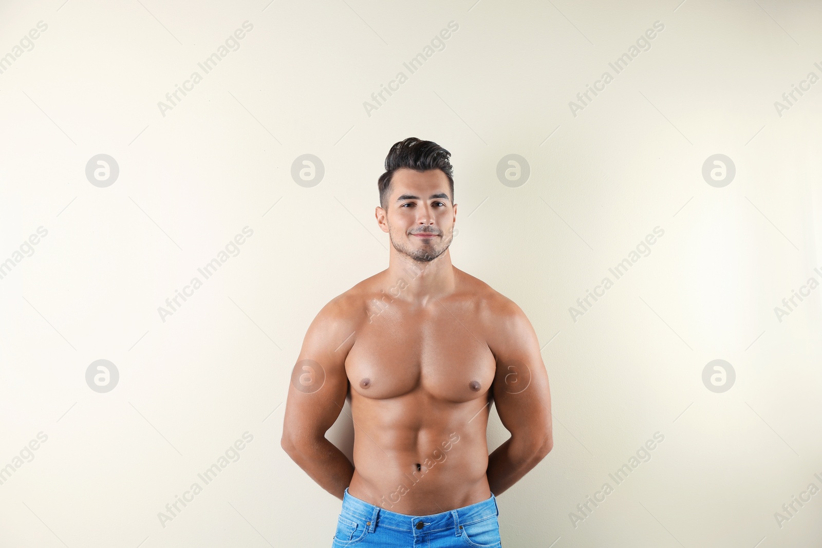 Photo of Shirtless young man in stylish jeans on light background