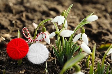 Photo of Traditional martisor near beautiful snowdrops outdoors, closeup. Beginning of spring celebration