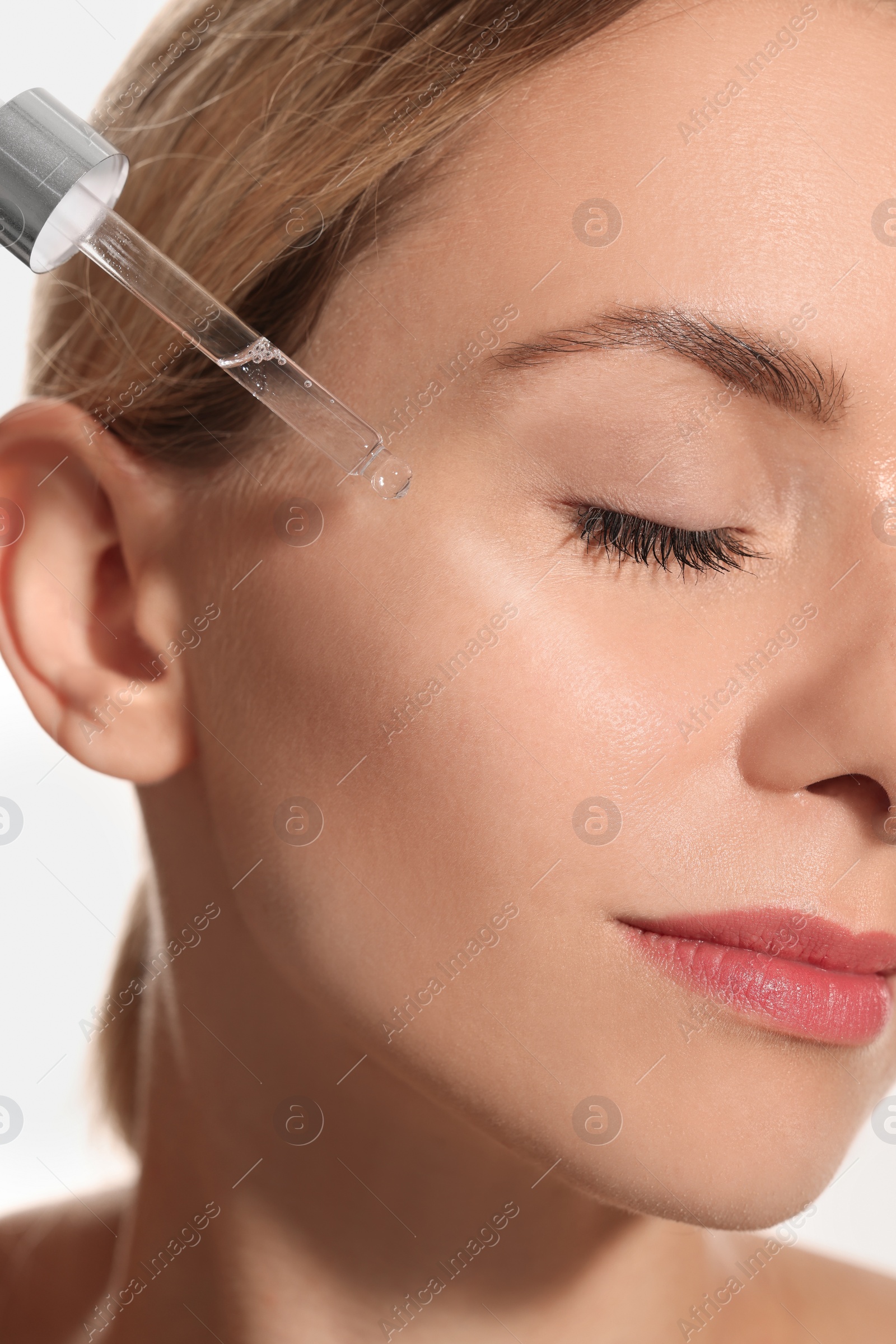 Photo of Woman applying cosmetic serum onto her face, closeup