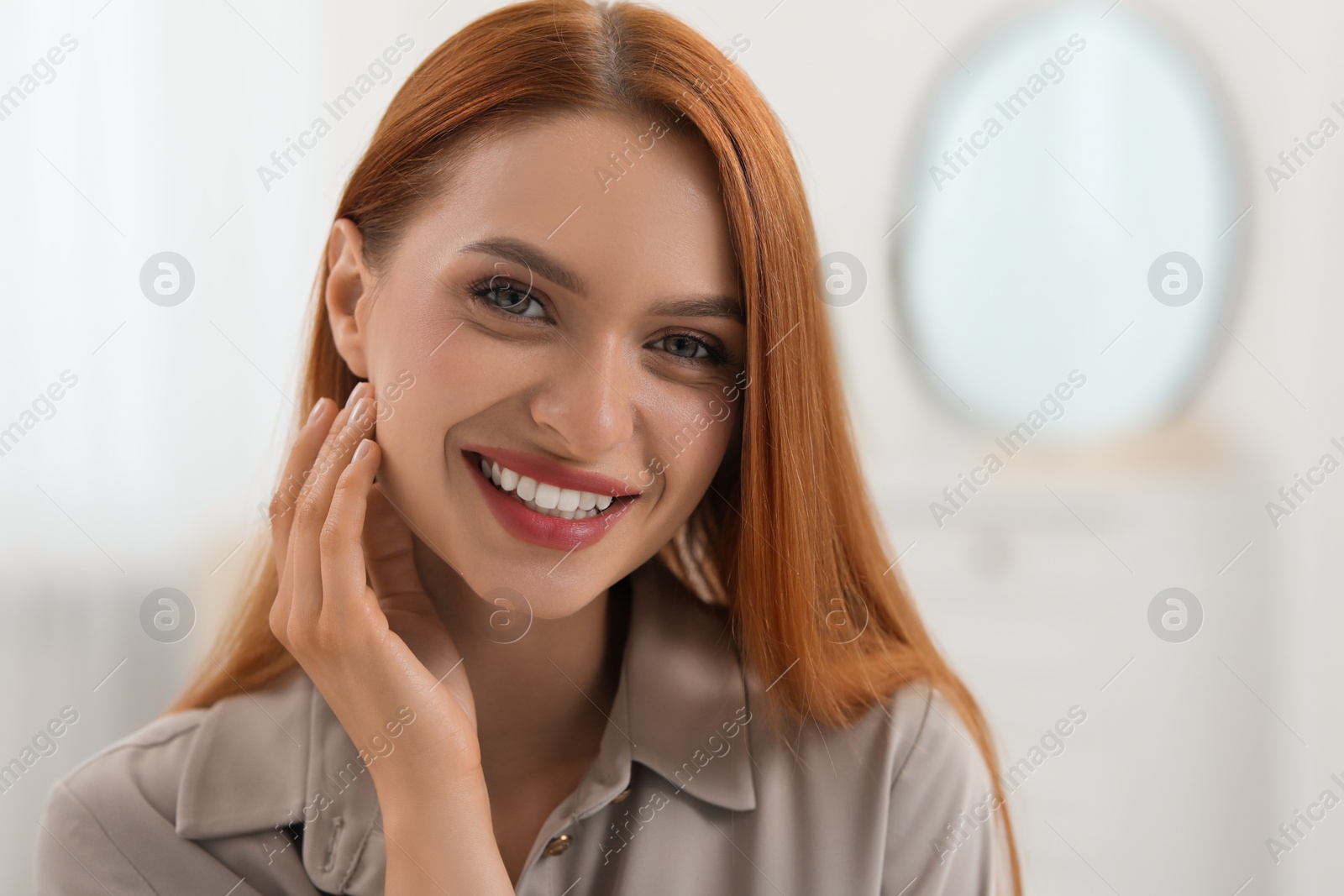 Photo of Portrait of beautiful young woman with red hair at home. Attractive lady smiling and looking into camera. Space for text