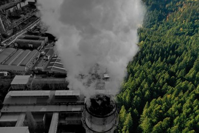Image of Environmental pollution. Collage divided with smoke into dense forest and industrial factory