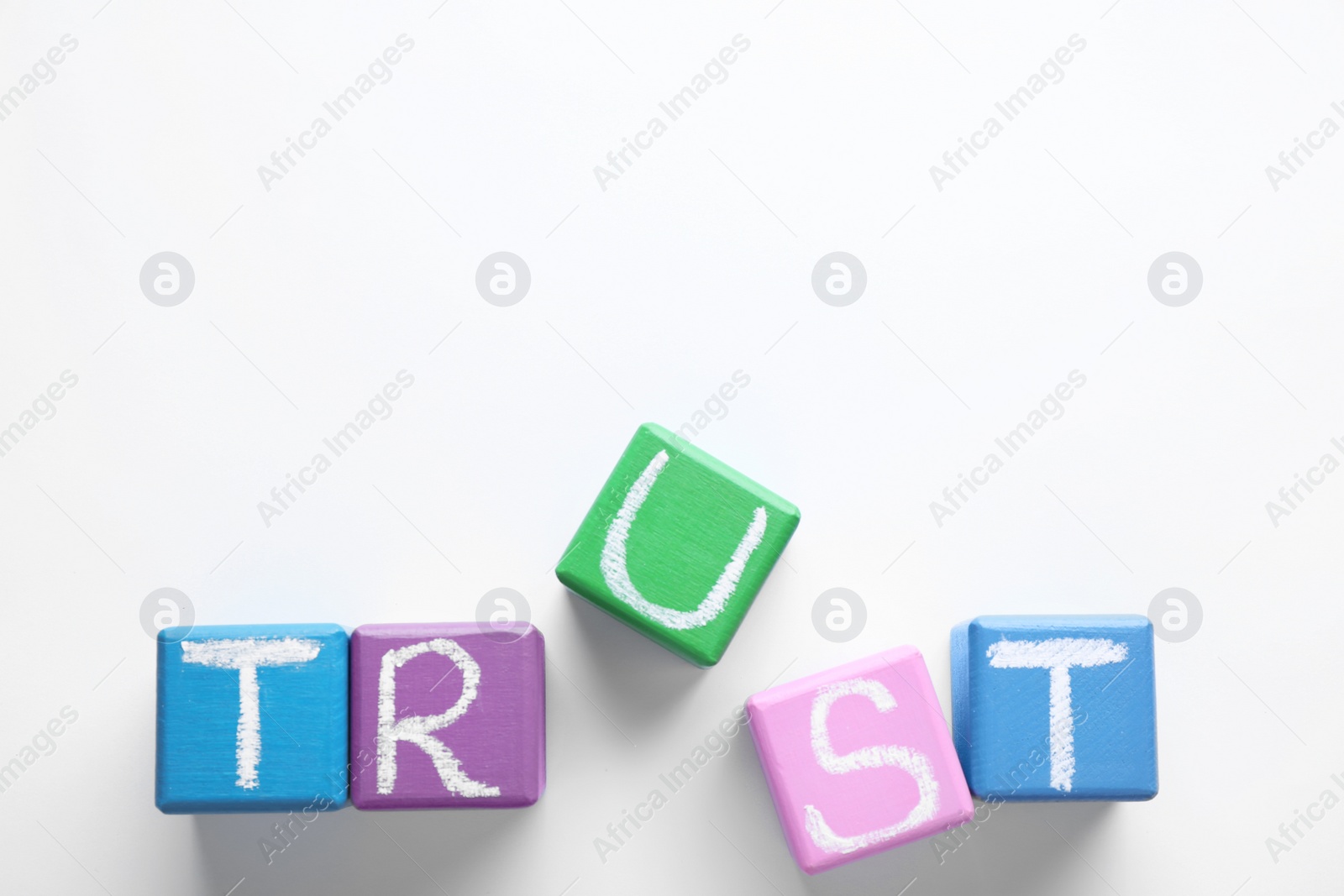 Photo of Cubes with word TRUST on white background, top view. Concept of jealousy