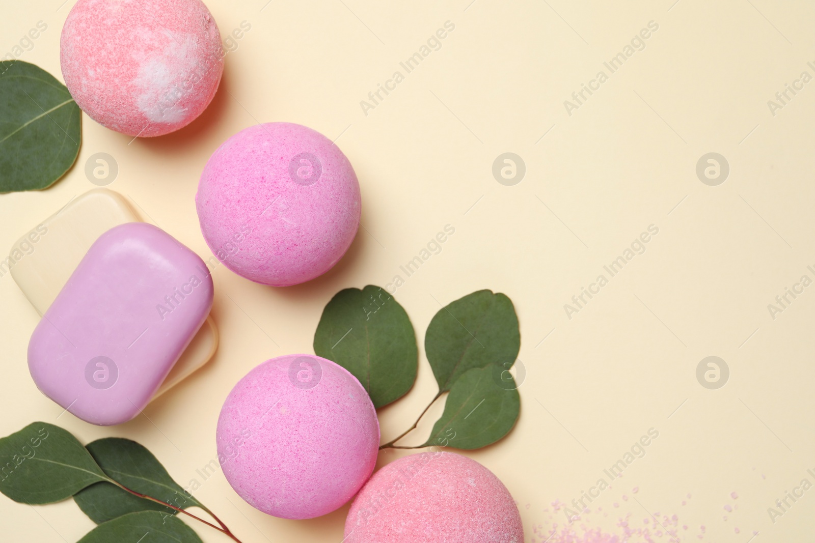 Photo of Bath bombs, eucalyptus leaves and soap bars on beige background, flat lay. Space for text