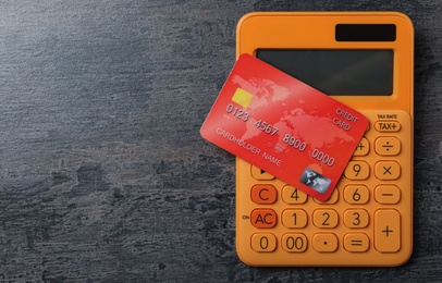 Credit card and calculator on grey table, top view. Space for text