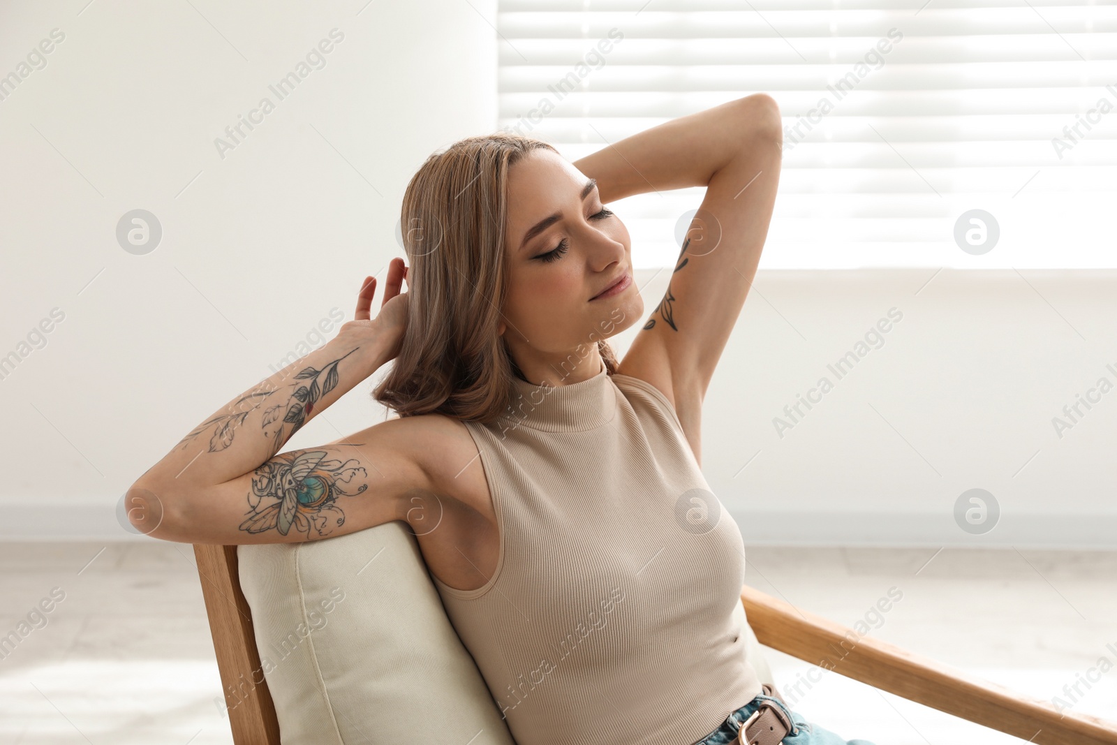 Photo of Beautiful woman with tattoos on arms resting at home