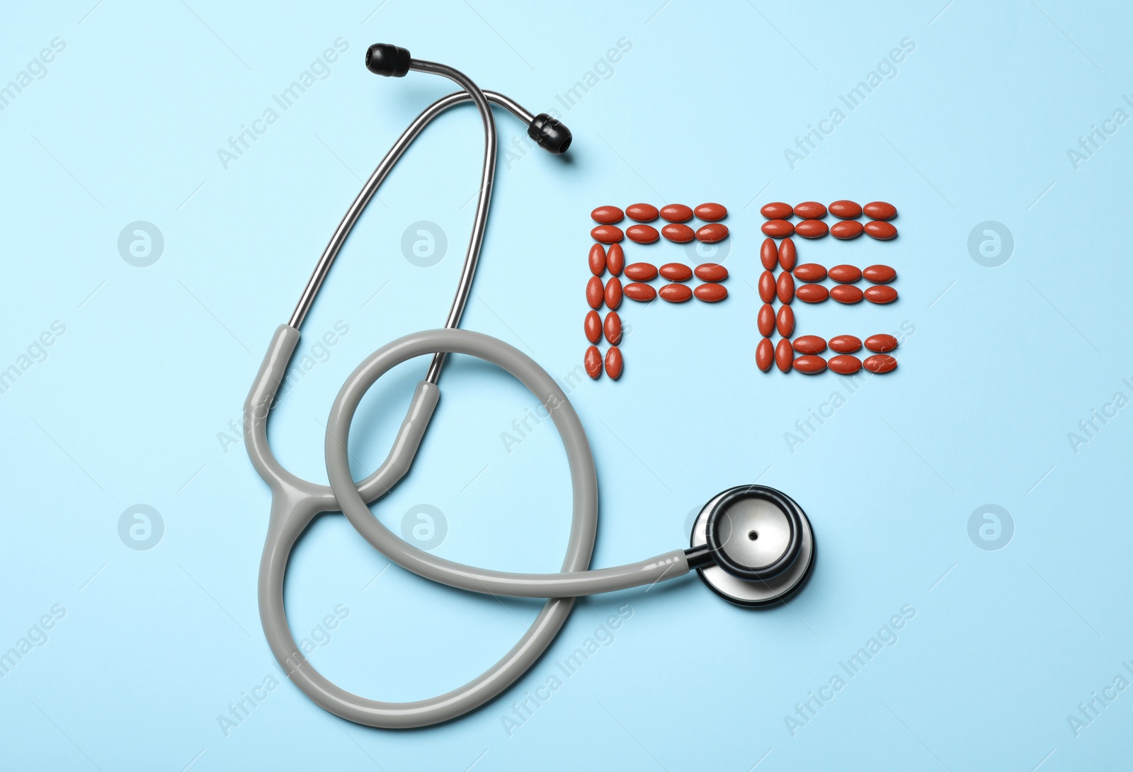 Photo of Pills and stethoscope on light blue background, flat lay. Anemia concept
