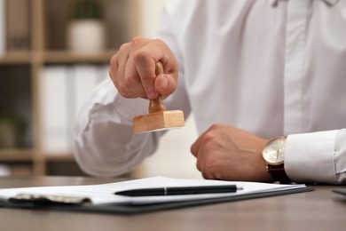 Photo of Man stamping document at table, closeup view