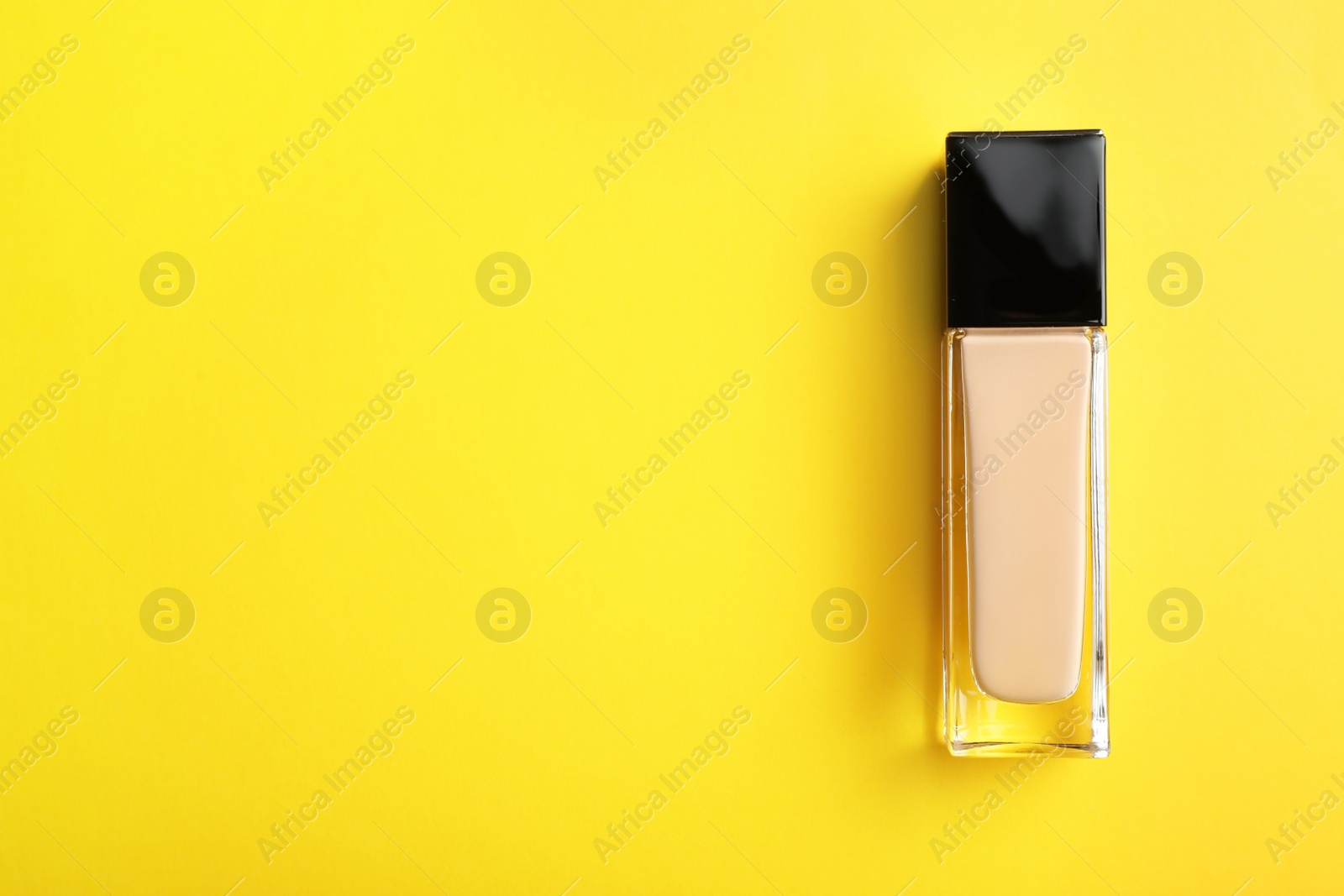 Photo of Bottle of skin foundation and space for text on color background, top view